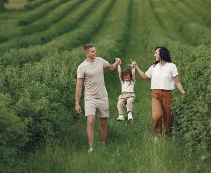 A happy family walking in a lush, green rural field together.