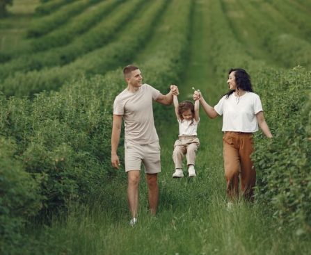 A happy family walking in a lush, green rural field together.
